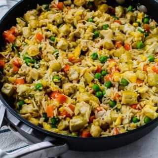 Vegetarian tofu fried rice in a skillet with crispy tofu, eggs, rice, and frozen vegetables.