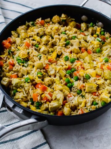 a black skillet filled with tofu fried rice and vegetables