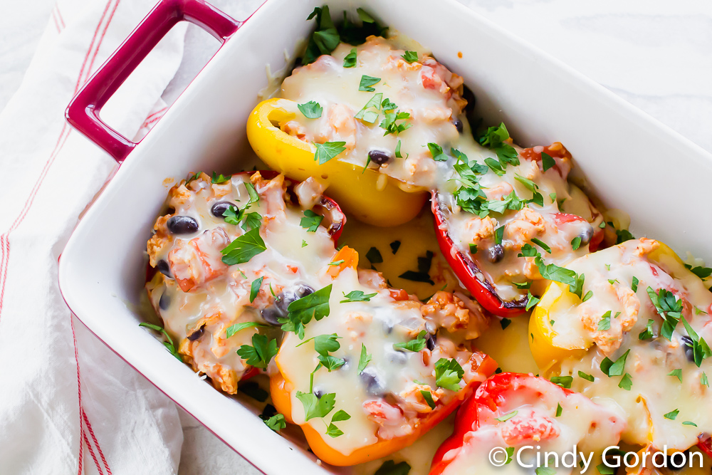 overhead shot of multi color stuffed peppers with white melted cheese and green herbs on top