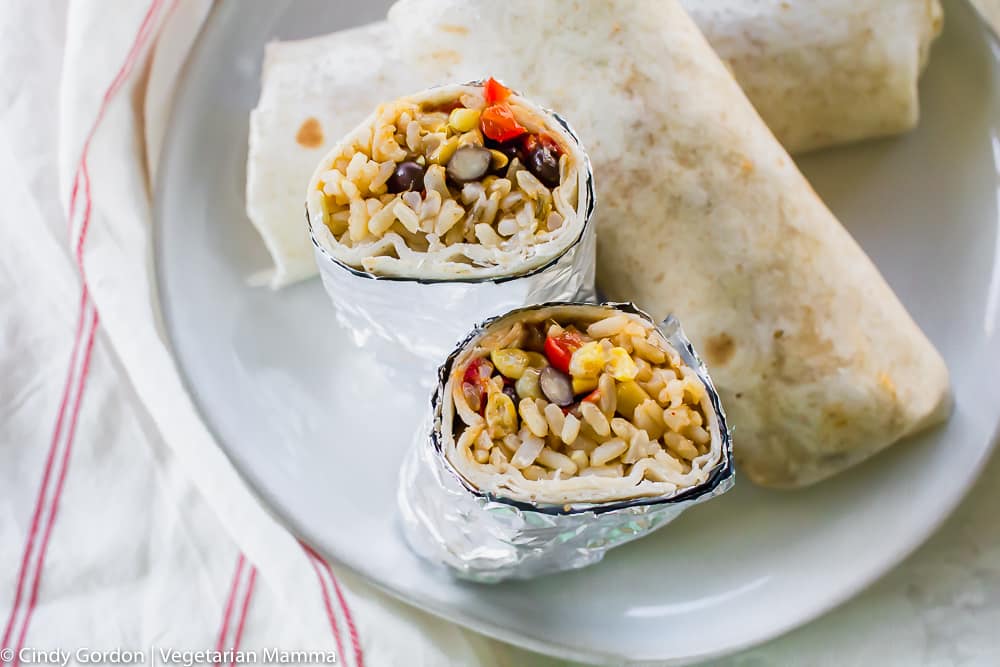 vegan burritos stuffed with rice, beans, and veggies on a round white plate