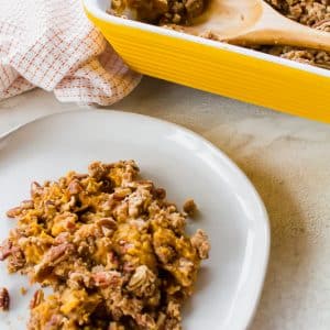 a portion of pecan topped sweet potato casserole on a white plate