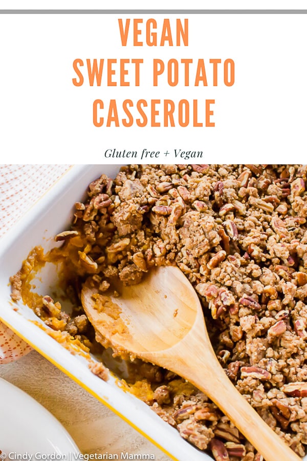 sweet potato casserole with pecan topping being served with a wooden spoon. 