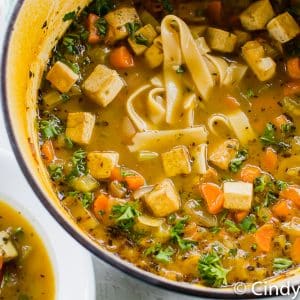 a pot of noodle soup with diced vegetables and tofu