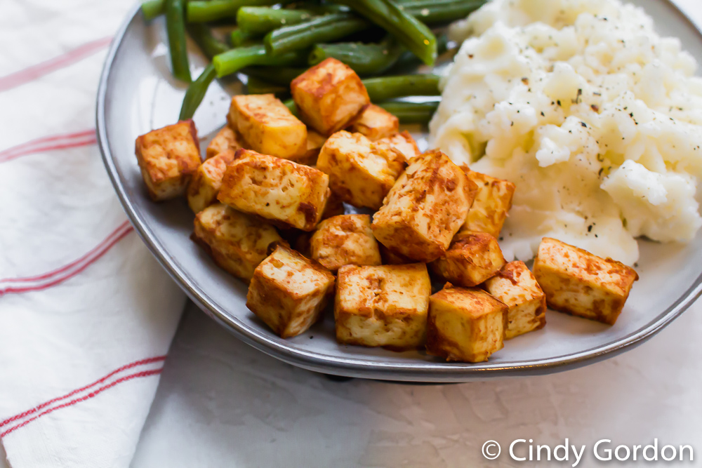 tofu dressed in barbecue sauce on a plate with rice and green beans
