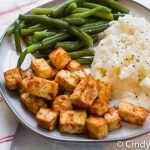 barbecue tofu squares on a plate with mashed potatoes and green beans