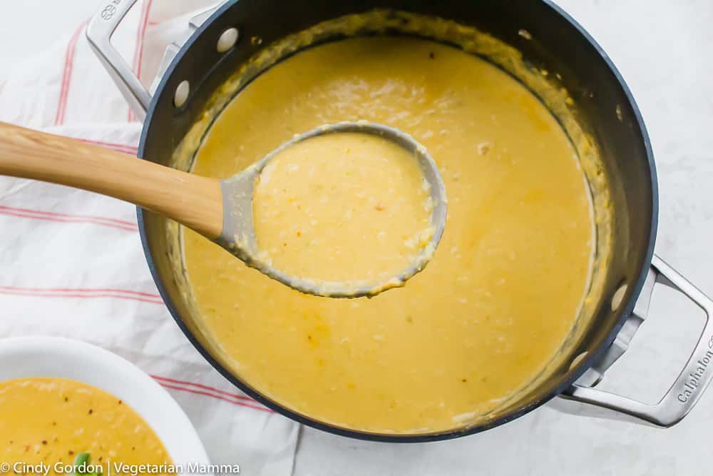 a pot of creamy corn soup being ladeled into a bowl.