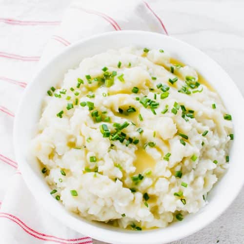 a bowl of mashed potatoes with melted butter and chives