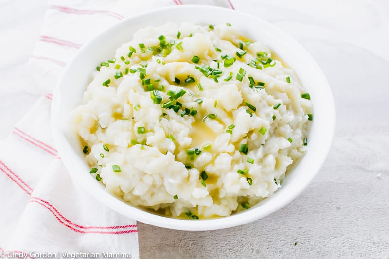 a bowl of mashed potatoes with chives and butter