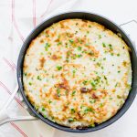 potato topped shepherd's pie garnished with green herbs in a skillet