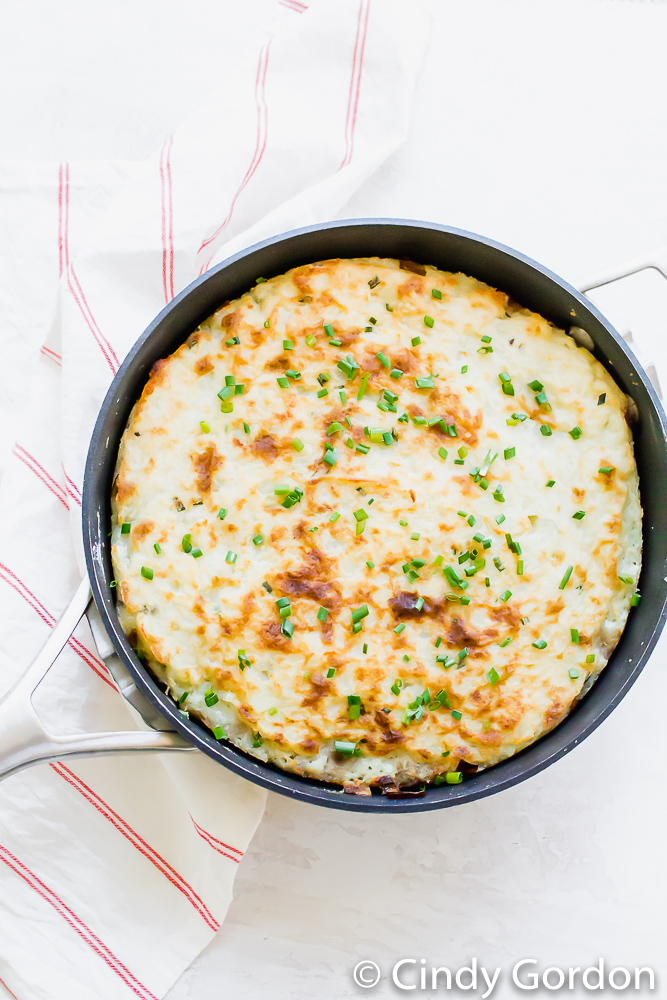 Mashed potato topped shepherd's pie garnished with green herbs in a skillet