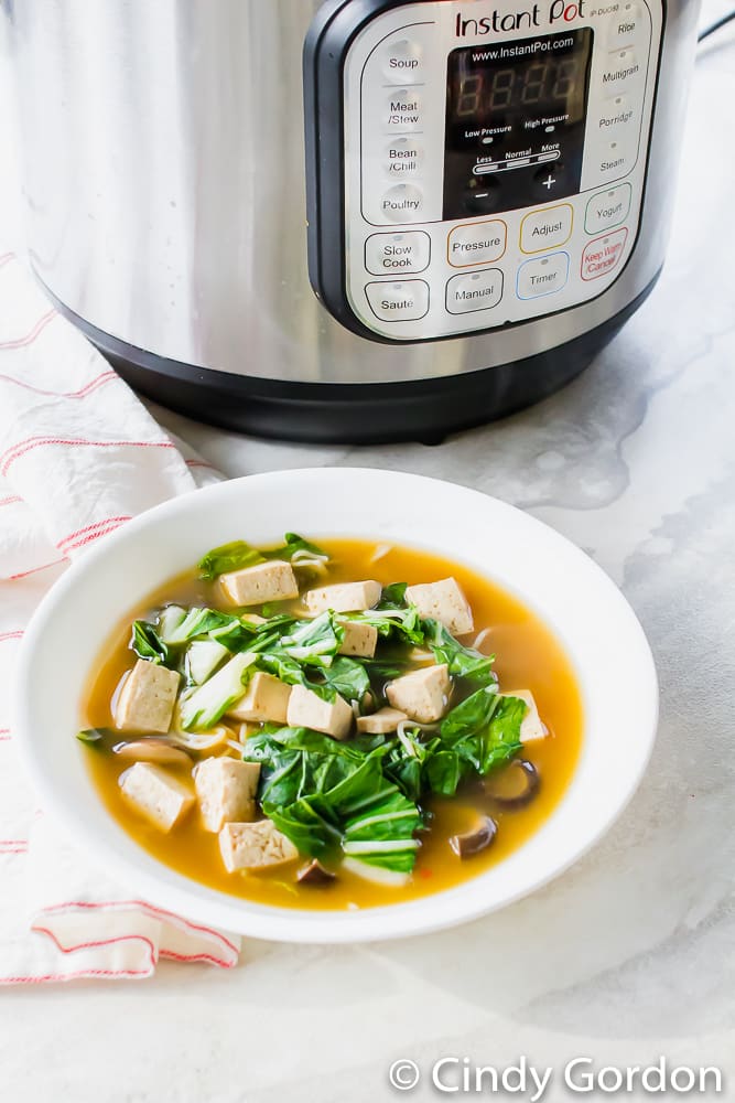 a bowl of ramen soup on a marble countertop next to an Instant Pot