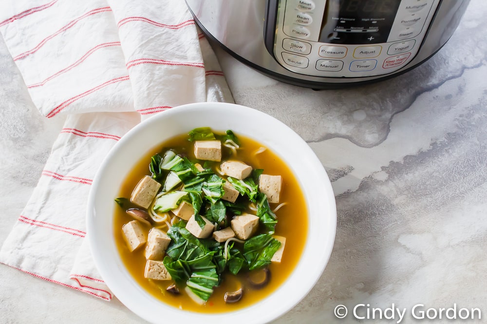 a bowl of ramen soup on a marble countertop next to an Instant Pot