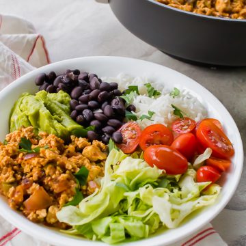 sofritas, lettuce, tomatoes, rice, black beans, and guacamole in a white bowl