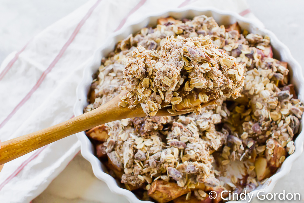 closeup of a wooden spoon with vegan apple crisp