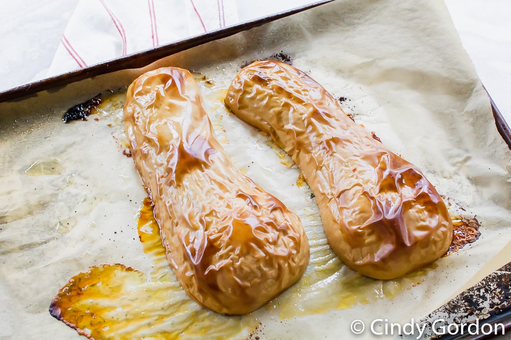 roasted butternut squash face down on a baking sheet 