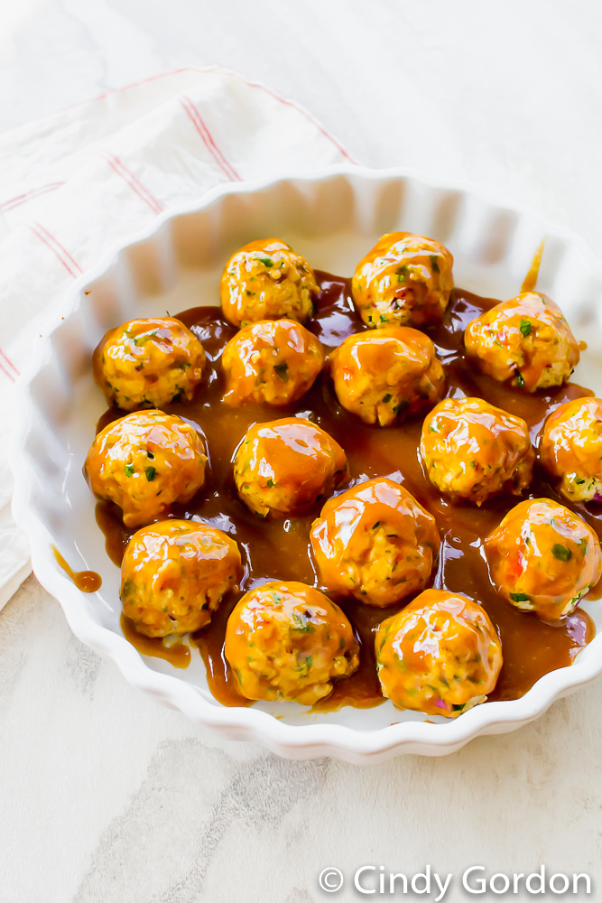 Tofu meatballs in a round baking dish glazed with brown sugar, ketchup, and dijon mustard