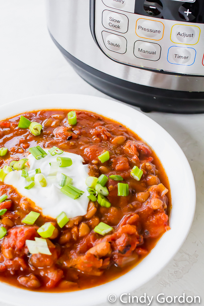 A bowl of vegetarian chili topped with sour cream and green onions