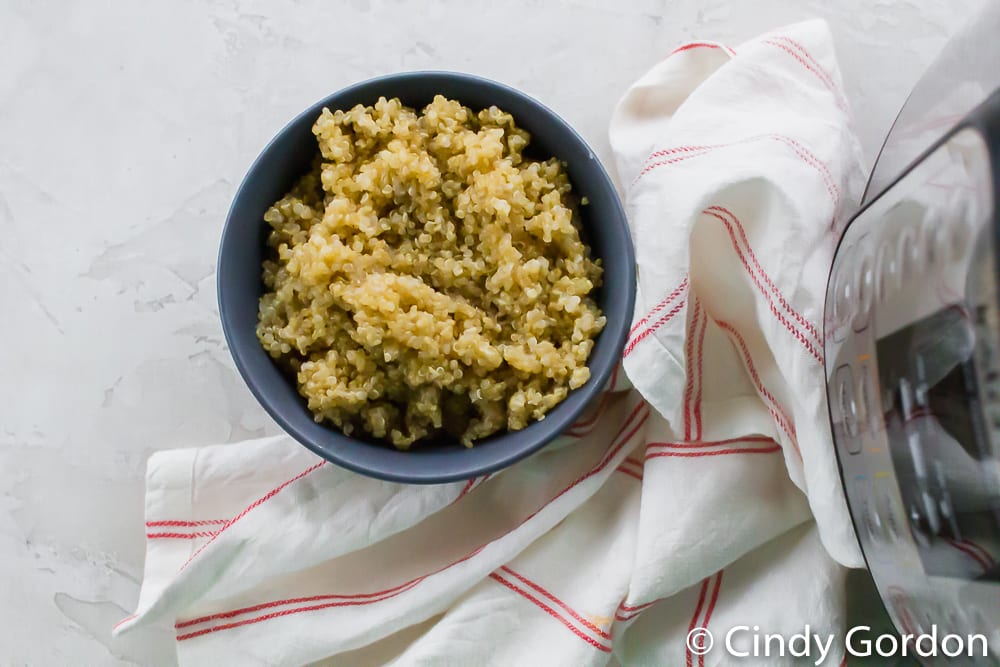 Overhead shot of quinoa in a bowl next to a red and white kitchen towel