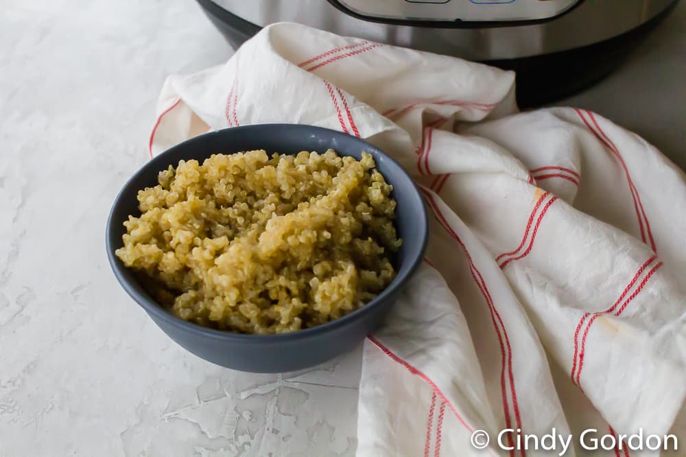 Quinoa in a blue bowl with a red and white kitchen towel and an Instant Pot