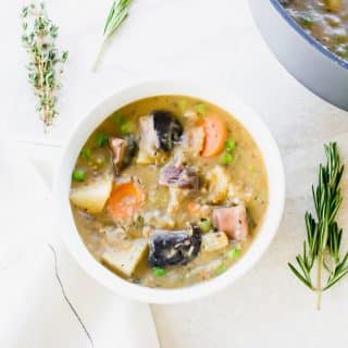 overhead shot of meatless beef stew in a white bowl on top of a white background