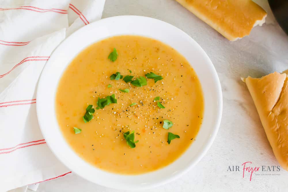 White round bowl of potato soup garnished with parsley and pepper