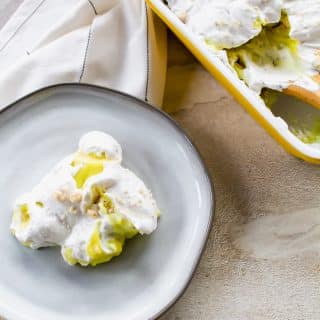 dollop of vegan banana pudding on a white plate, a napkin thrown down to the top left and on the top right of the vertical photo a yellow 8x8 dish with white inside has the pudding