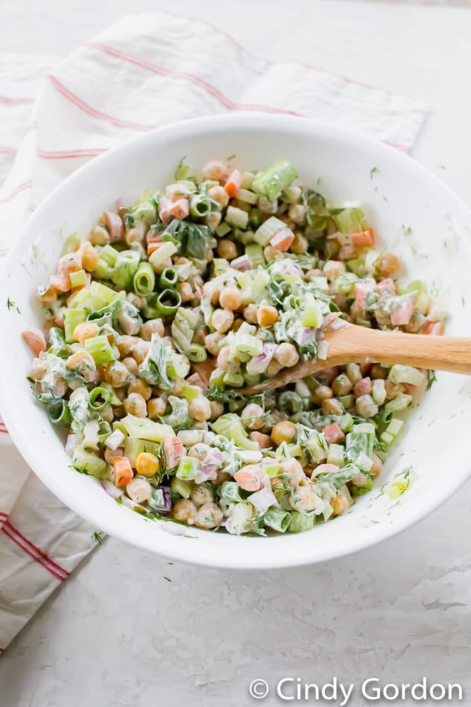 Chickpeas, celery, carrots, scallions, and vegan mayonnaise in a white bowl