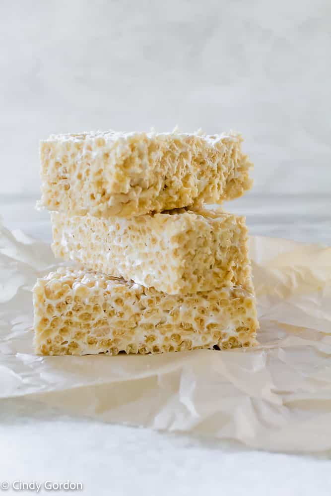 A stack of three vegan rice krispie treats on parchment paper