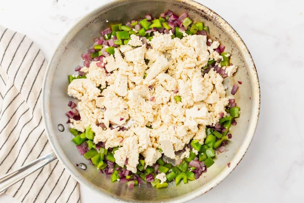 metal skillet with with peppers, onions and tofu