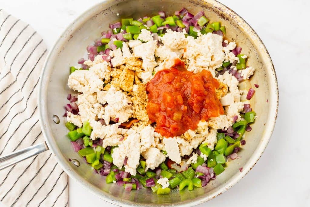 metal skillet with with peppers, onions and tofu sauces and spices