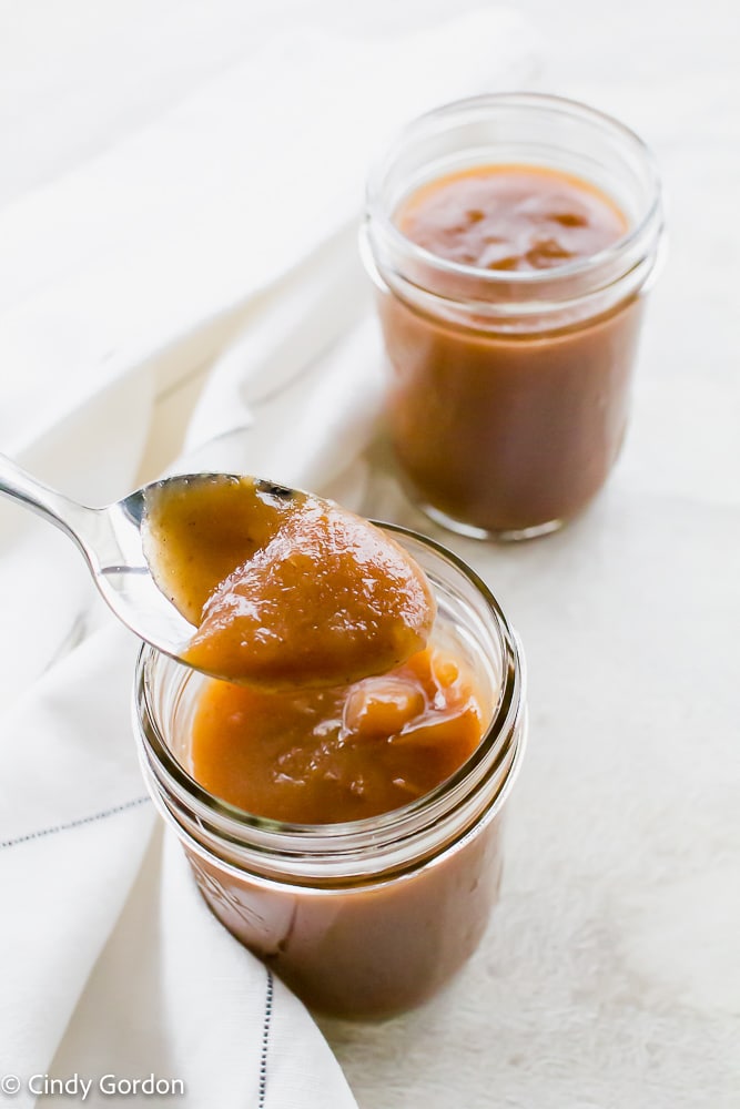 A spoonful of apple butter over a full jar next to another mason jar