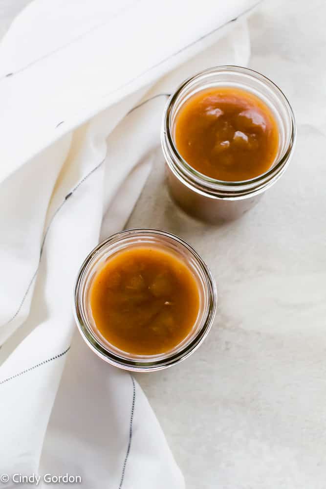 An overhead shot of two mason jars of Instant Pot apple butter with a white kitchen towel