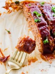 sliced meatloaf on parchment paper, made from beyond meat. a fork is holding a bite.