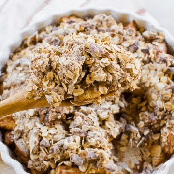a white round baking dish filled with apple crisp topped with crispy oats.