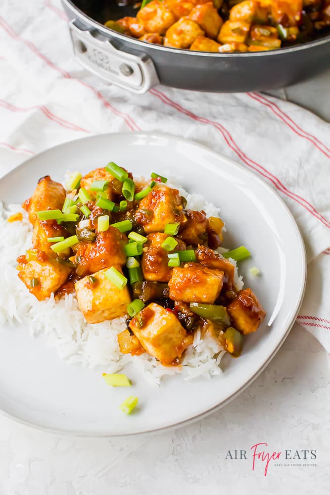 Tofu cubes in a brown sauce with onions and peppers over white rice