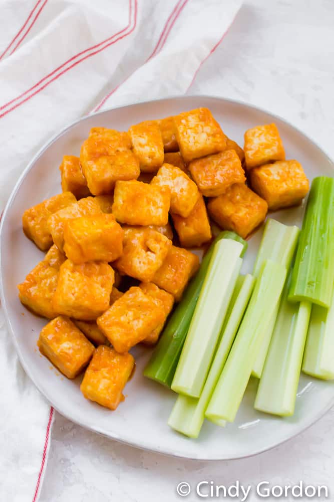 Crispy tofu smothered in vegan buffalo sauce with celery sticks