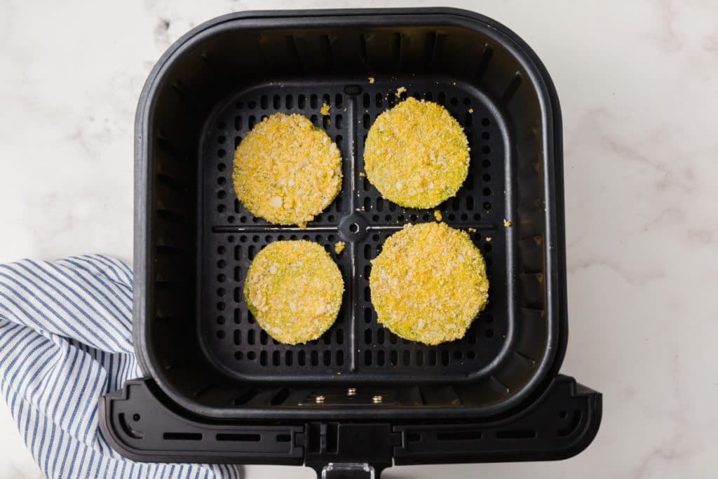 breaded fried green tomatoes in a black air fryer basket