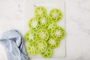 sliced green tomatoes in a white cutting board