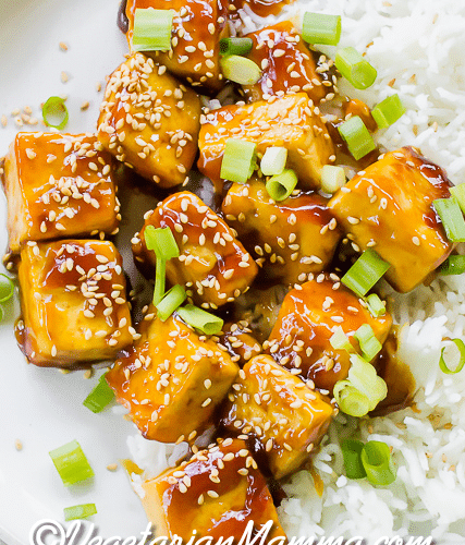 Close up shot of the Sticky, crispy sesame tofu on a white plate with white rice.