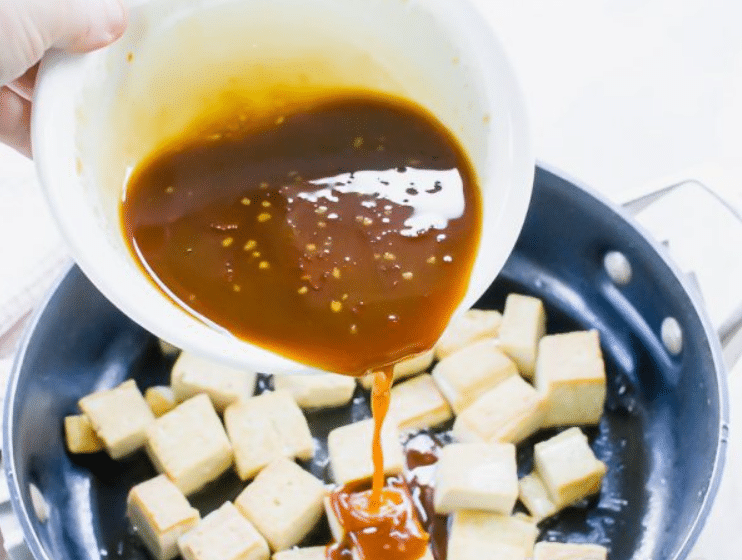Sticky, sesame sauce poured over the crispy tofu in a pan.