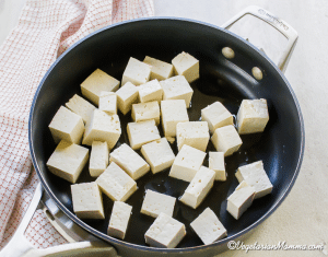 Cut the tofu into bite-sized pieces. Sauté it in a skillet with sesame oil over medium heat for about 10 minutes, flipping occasionally.