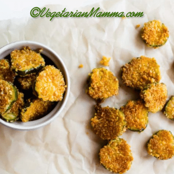 A white bowl of gluten-free fried pickles and a few pickles on parchment paper.