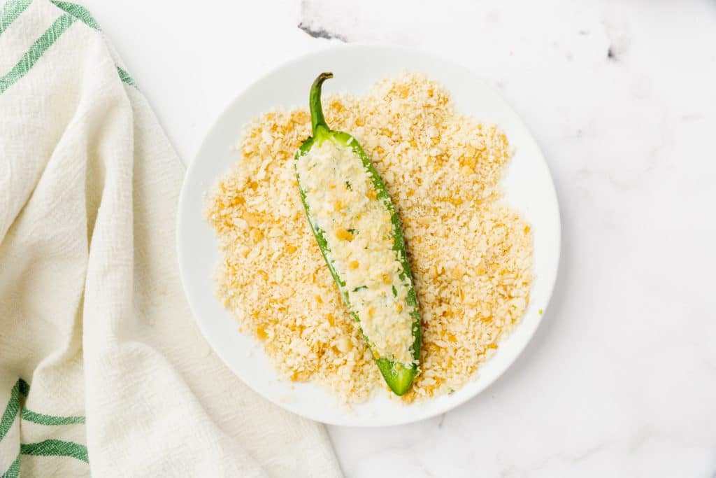 white bowl of bread crumbs and a half of air fryer jalapeo pepper in it
