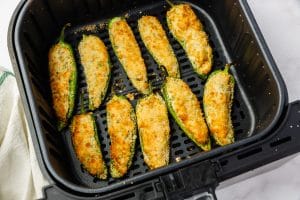 black air fryer basket with golden brown air fried jalapeno poppers