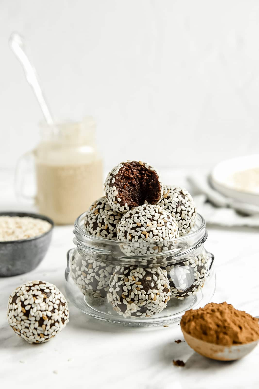 A glass jar of chocolate tahini balls coated with sesame seeds