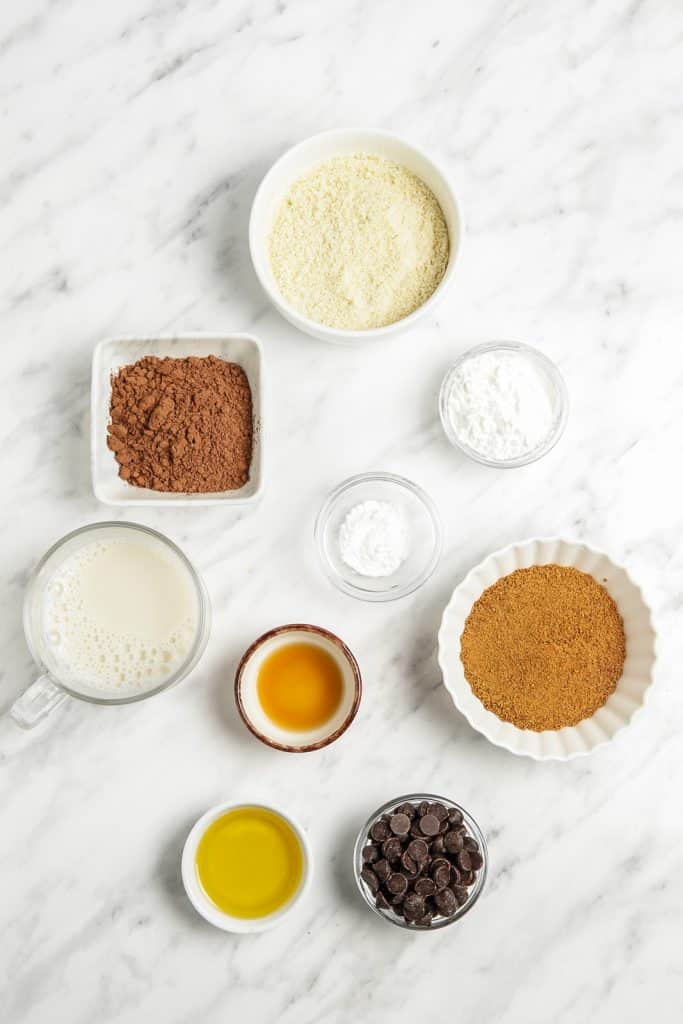 bowls of almond flour, coconut sugar, cocoa powder, plant-based milk, vanilla extract, and dark chocolate chips