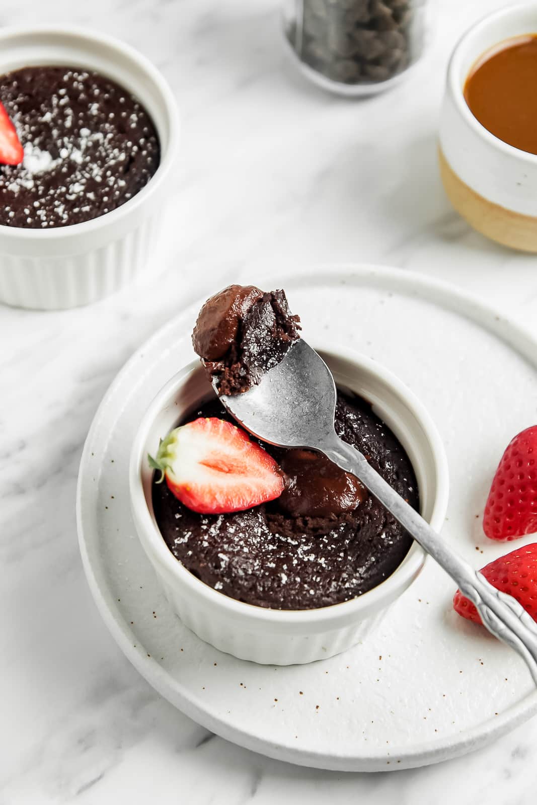 A bite of vegan chocolate mug cake on a spoon over the cake