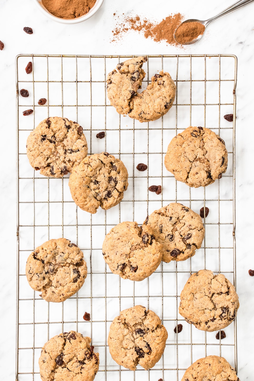 10 oatmeal raisin cookies on a cooling rack next to a pile of cinnamon