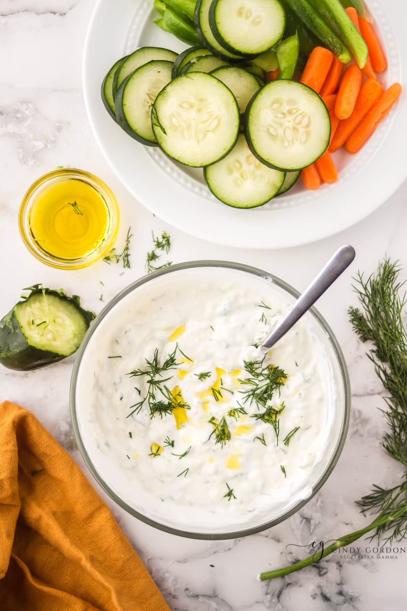 Overhead shot of a bowl of tzatziki sauce garnished with dill and a little olive oil