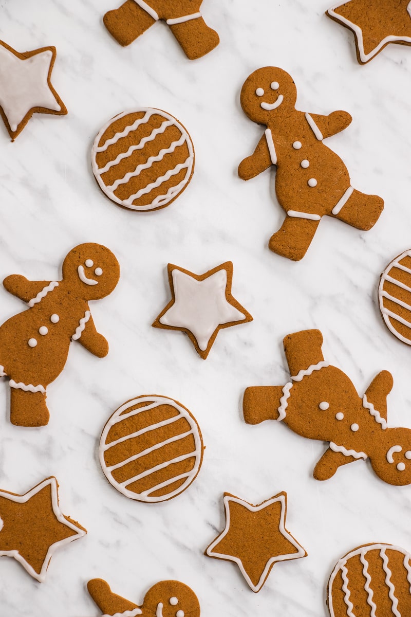 Gingerbread people, stars, and ornaments spread out on a marble countertop